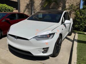 White Tesla Model X with marked front fender and bumper collision damage before repair at Premier Coach Auto Collision.
