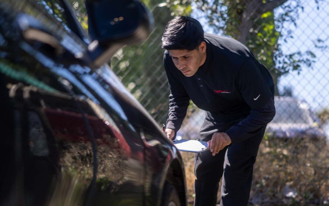 Technician evaluating vehicle body damage before lease return