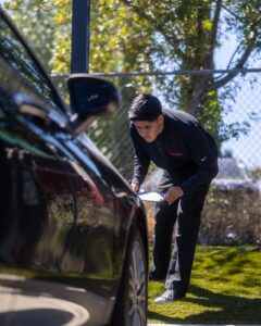 Technician performing an initial damage assessment on a Tesla Model Y at Premier Coach Auto Collision