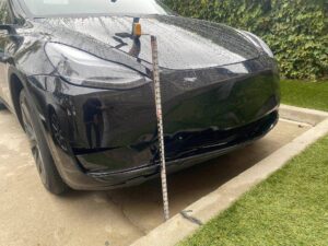 Tesla Model Y front bumper being inspected for collision damage before repair